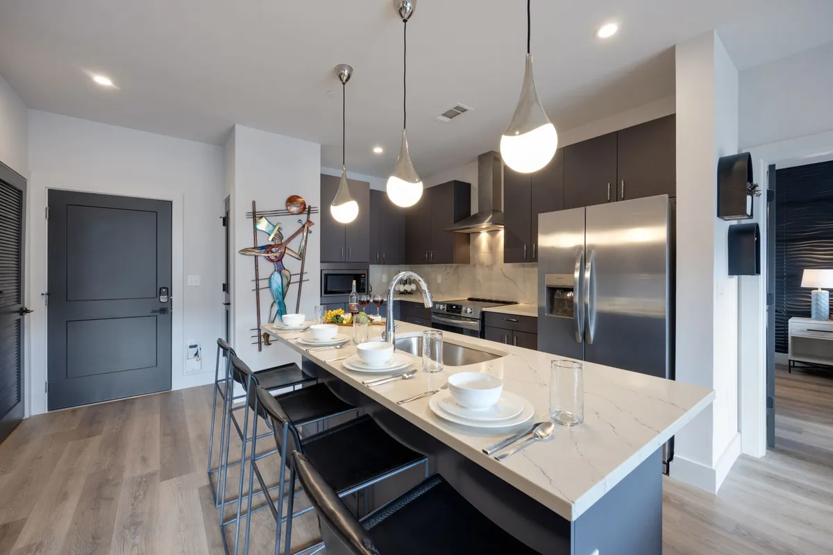 A bright, stylish interior kitchen scene featuring a modern island, a sculptural art piece, and high-end appliances. The room exudes a welcoming, contemporary vibe, perfect for both entertaining and relaxing after exploring the city.