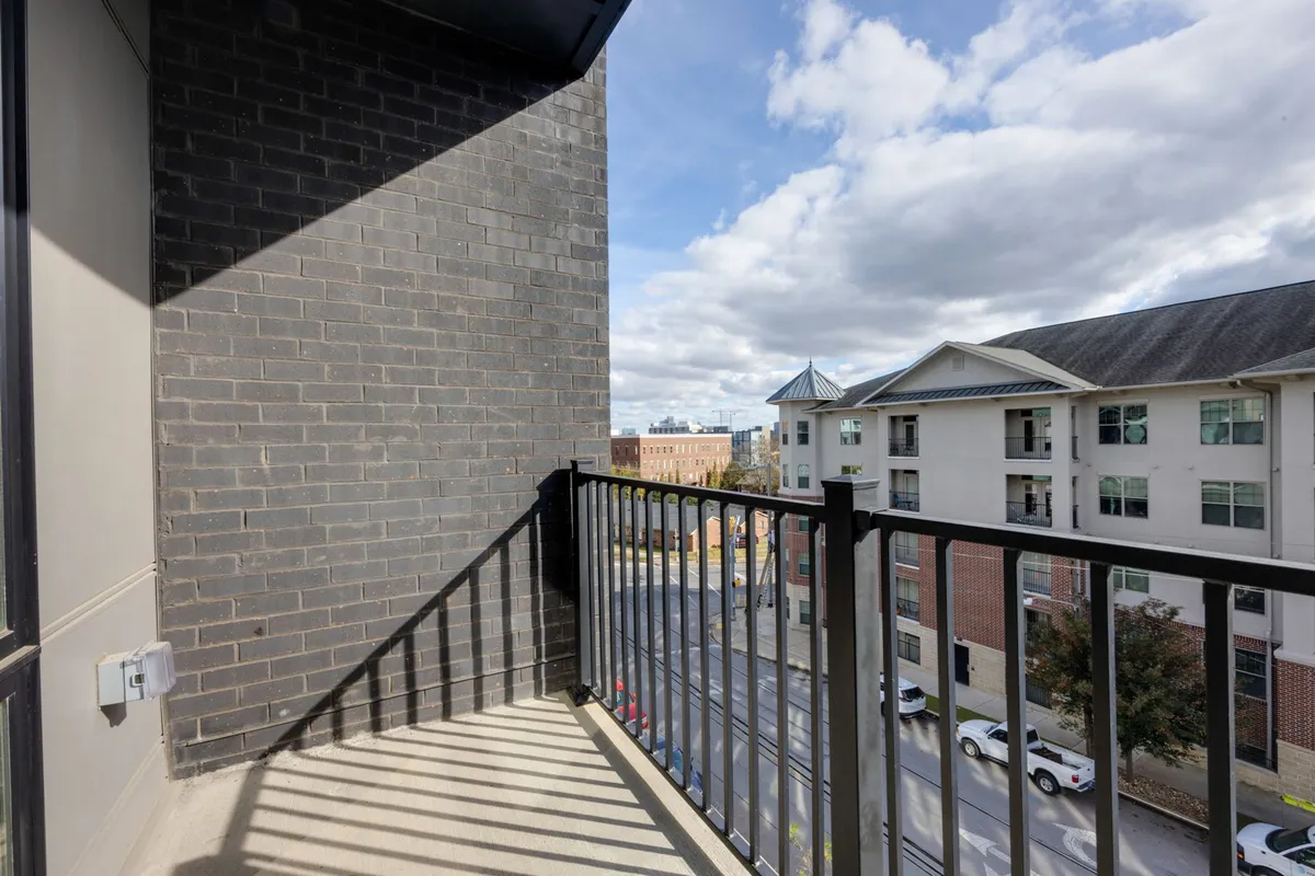 A private balcony with a modern railing, overlooking surrounding city buildings and open sky. The space is ideal for relaxing with a morning coffee or enjoying a sunset toast, with the city’s energy just beyond your doorstep.